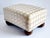 A very decorative rectangular foot stool with a beautiful light beige and gray diamond cut pattern, silk and textured...