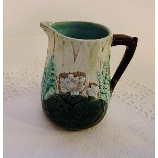 Antique Majolica Creamer Pitcher, Embossed in Earthtone colors with green leaves, flowers and fern. Measures 4"tall, 3.5"...