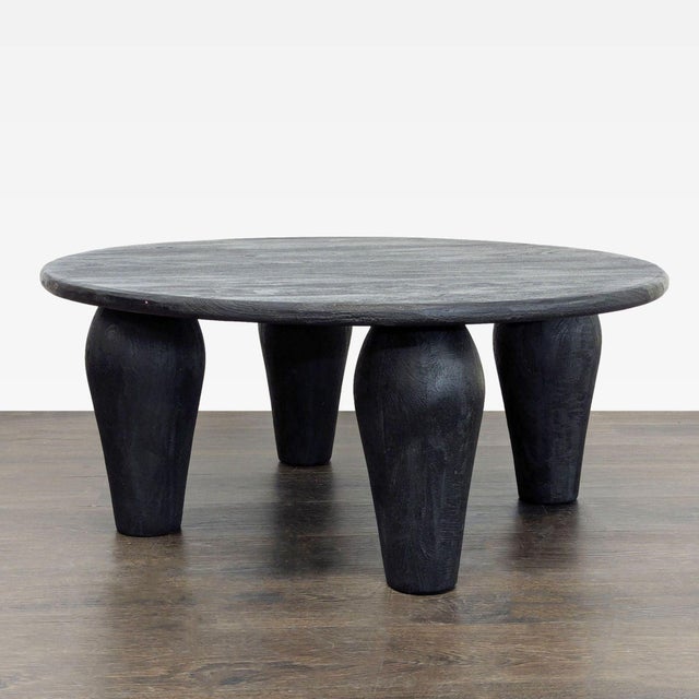Substantial legs support a slim, rounded tabletop of light black-finished reclaimed wood, for a global, organic look and...