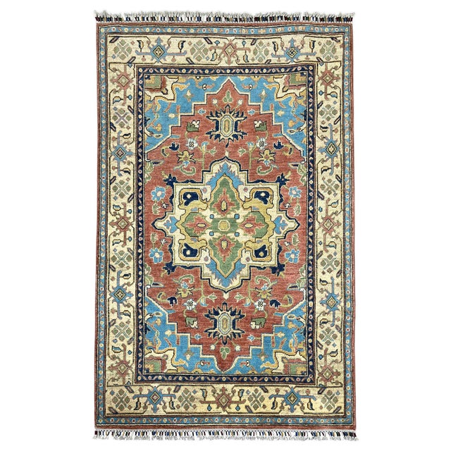 This naturally dyed wool rug pairs a terracotta field with a bold central Heriz medallion. Sky blue corners, soft green...