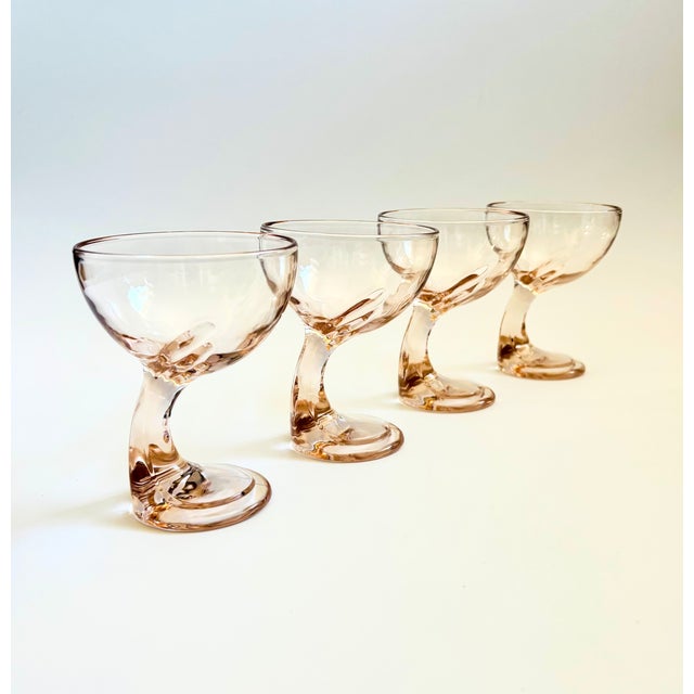 A set of 4 vintage pale pink glass coupes. Beautiful art deco design with large round bowls and curved offset stems. Made...
