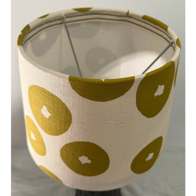Decorative lampshade crafted from a natural linen textile printed with an oversized, rhythmic dot motif in a warm olive-...
