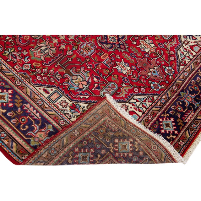 Beautiful vintage Persian Tabriz hand-knotted wool rug with a red color field. This piece has a navy blue frame and...