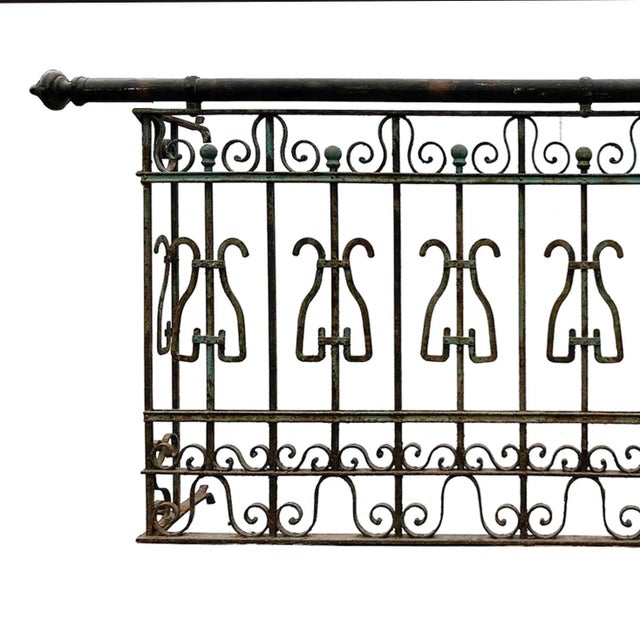 Antique wrought iron balcony railing featuring decorative scrollwork. Transitional Art Nouveau to Art Moderne style.