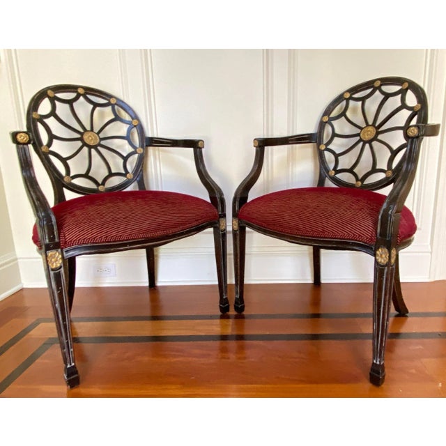 A lovely pair of vintage, spider-back arm chairs in a classic Hollywood Regency silhouette, with dark stained wood, carved...