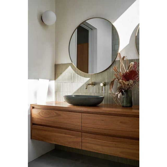 This large round mirror is a stunning addition to any room. The frame is made of thick, durable brass with a unique tick...