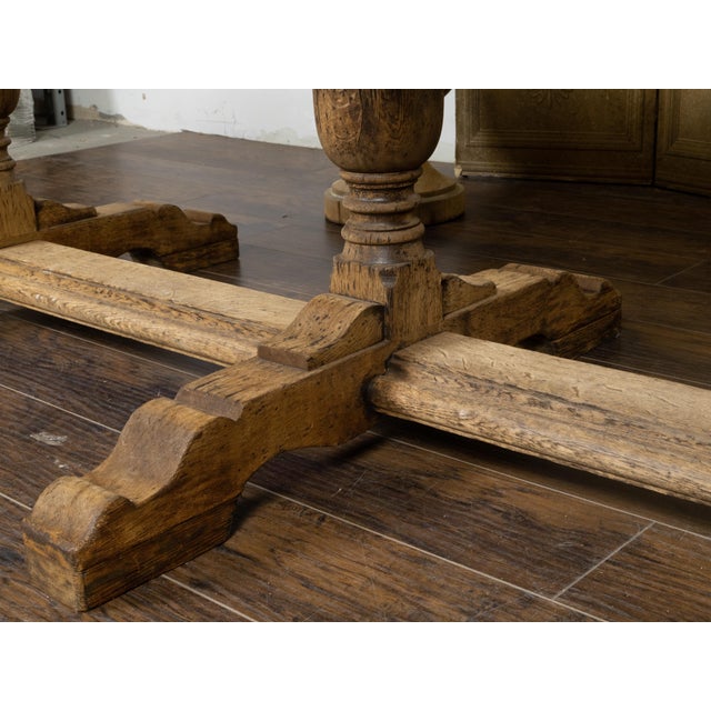 A French bleached oak farm table from the 19th century, with trestle base, baluster legs and weathered patina. Created in...