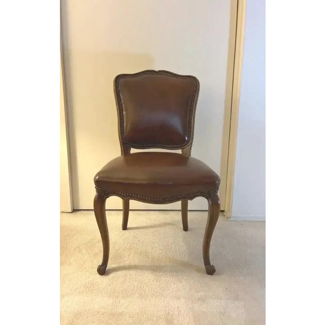 Elegant side chair featuring rich brown upholstered seat and back accented with decorative nailhead trim. The chair...