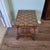 This vintage curule style stool features a carved wooden base paired with a geometric-patterned fabric seat. A classic...