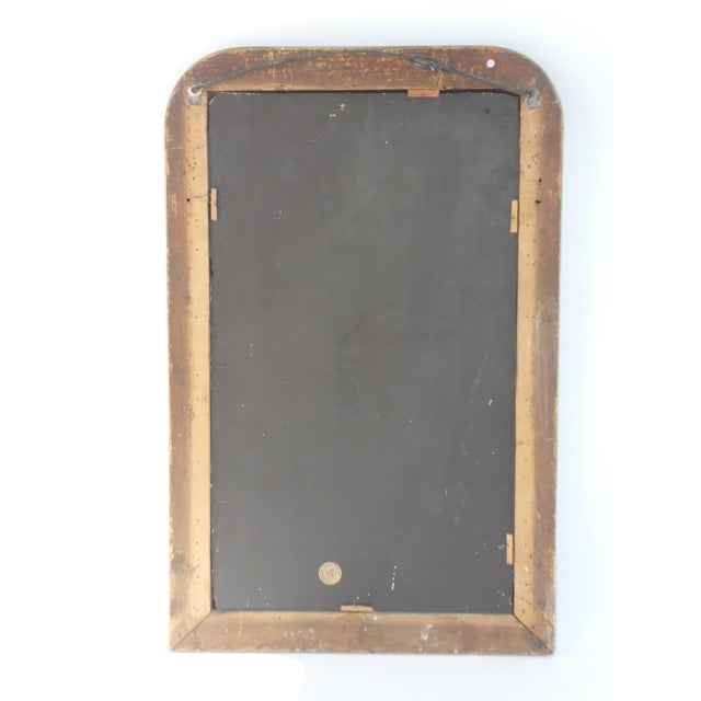 An antique French Louis Philippe style wall mirror with an ornate golden gilded frame with a floral pattern. The mirror is...