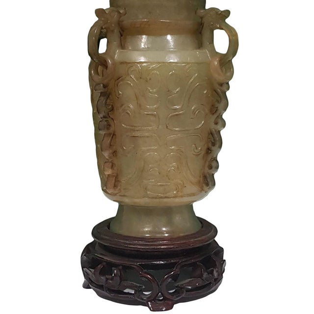 Green Jade with wooden base friezed with decorations representing plants and vegetation. Measure: 25 x 10 x 10 cm (with...