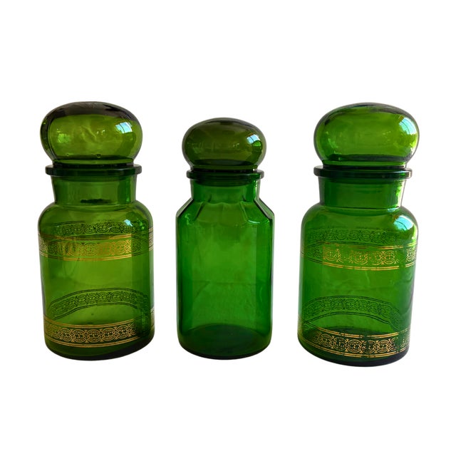 A striking trio of Belgian cobalt green apothecary jars, their rich translucent glass wrapped in delicate gilt ornamental...