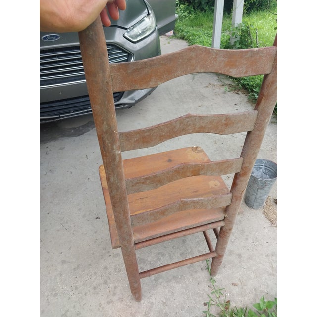 For sale is a charming Early American primitive-style wooden ladderback side chair. This standalone piece features a...