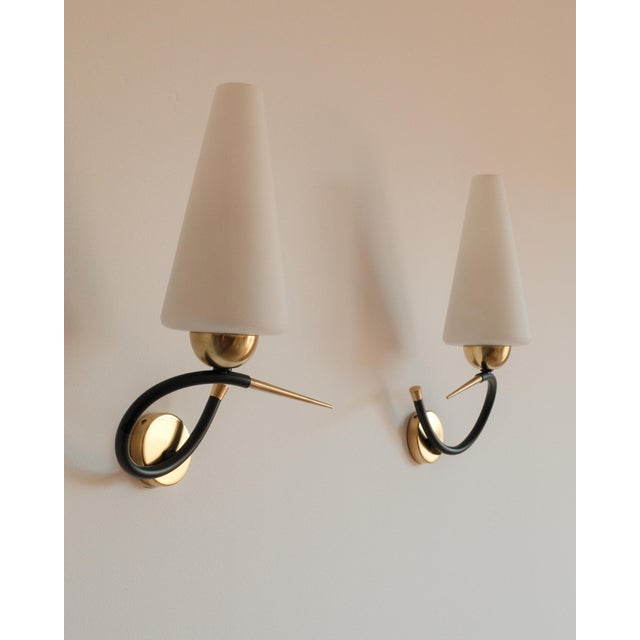 An elegant pair of French whiplash sconces attributed to Arlus or Lunel, embodying the refined dynamism of mid-century...