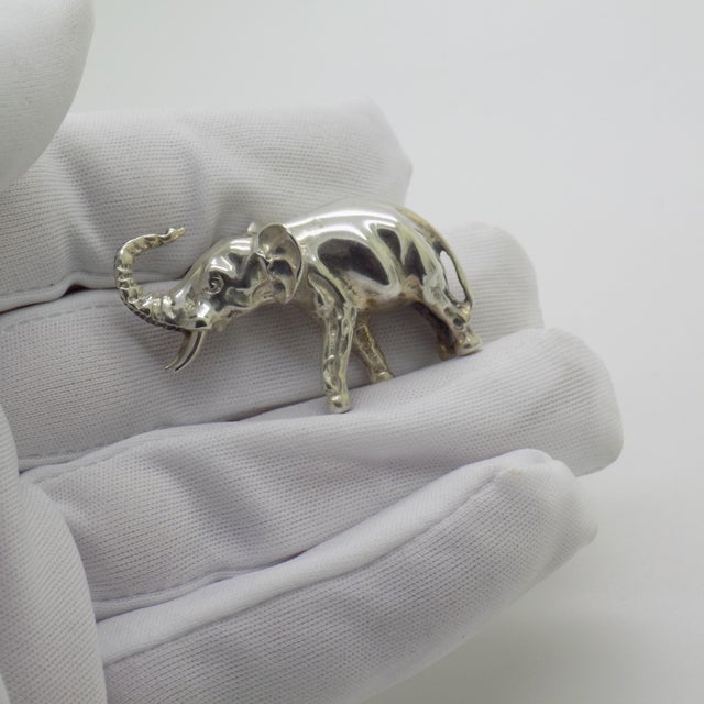 This vintage silver decorative object depicts a detailed elephant figurine miniature with tusks, crafted as a cabinet...