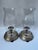 A matching pair of vintage silver plate round footed taper candle holder with hourglass shaped colorless glass hurricane...