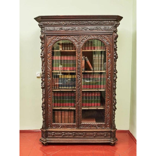 Neo-Renaissance bookcase made of solid oak, richly decorated with hand-carved decor with motifs of leaves, flowers, fruits...