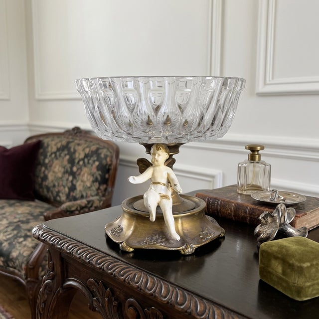 Vintage Hollywood Regency compote candy dish featuring a clear pressed glass bowl set into a decorative figural base. The...