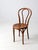 This antique Thonet-style café chair features traditional bentwood craftsmanship with a gracefully curved frame and a...