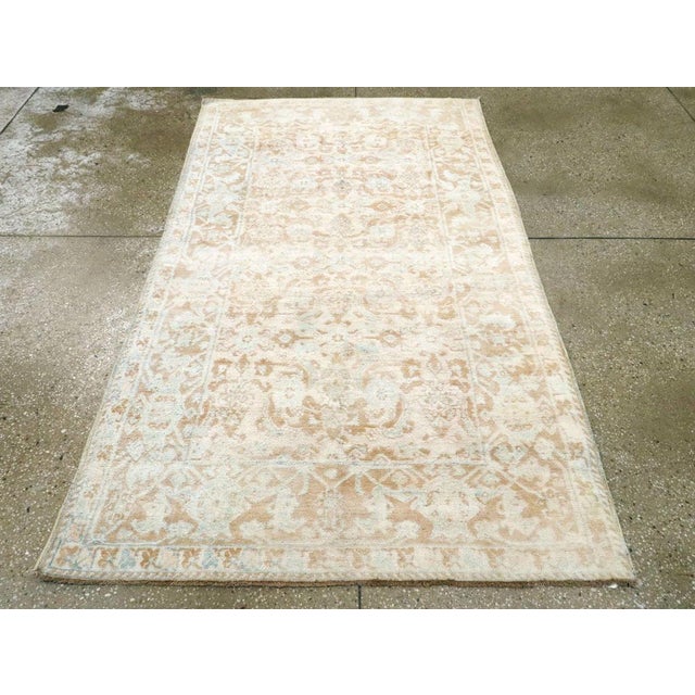 A vintage Indian Cotton Agra rug. A modified allover Herati pattern in beige and ecru softly covers the rust field of this...