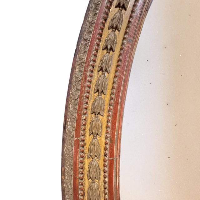 This is a lovely, decorative oval wall mirror with an ornate, classical-style frame. It was made in England in the mid...