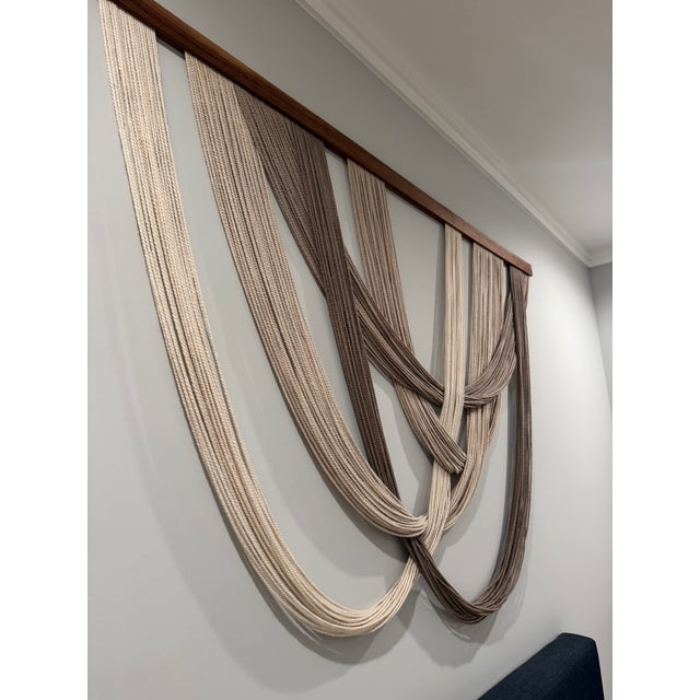 This is an original handcrafted fiber art wall hanging by Le Lo Boho, featuring the artist’s signature draped composition...
