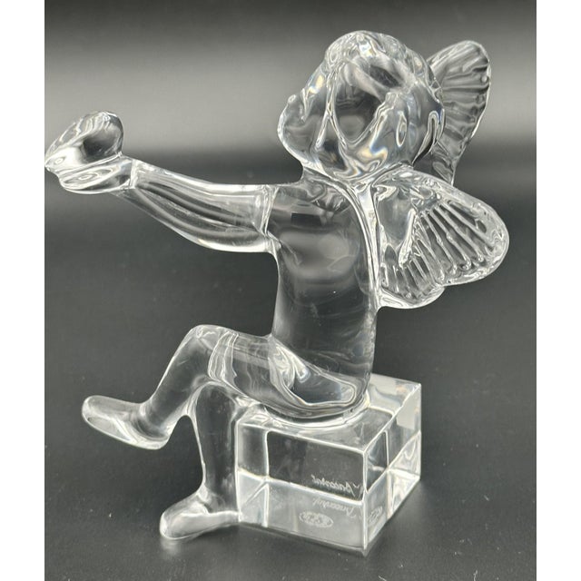 A beautifully crafted Baccarat crystal cherub figurine, featuring a seated angel holding a trumpet atop a solid crystal...