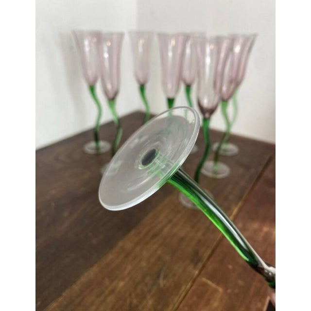 Elegant hand-blown glass champagne coupes. On a translucent base, the coupe has a fluid, slender shape with a twisted...