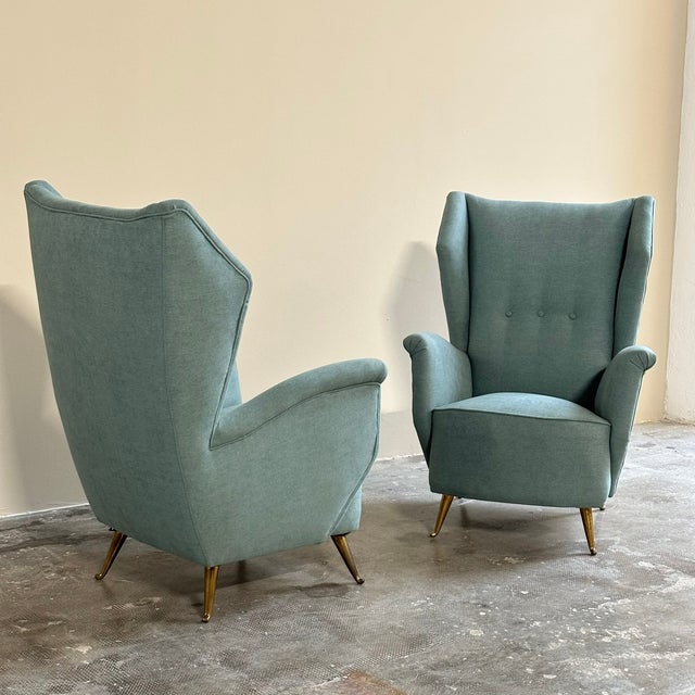 A pair of 1950s armchairs, Italian-made by Isa Ponte San Pietro. The armchairs feature a solid frame upholstered in a...