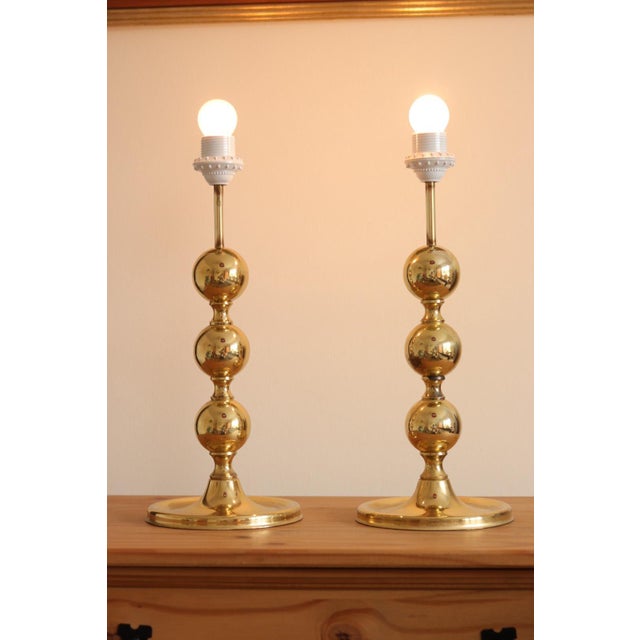 Two exquisite polished brass table lamps featuring a delightful round bobbin-style design. These lamps have undergone...