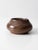 A vintage handmade pottery vessel with a rounded low form and rich brown glaze layered with subtle earthy tonal variation....