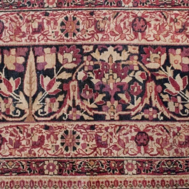 An early 20th Century Persian Kirmanshah carpet with central floral medallion on a cranberry background surrounded by a...