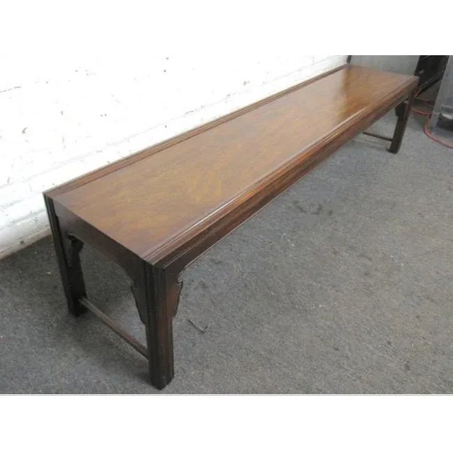 Long and low coffee table with a subtle Asian influence. Beautiful walnut grain runs down the top with decorative scrolls...