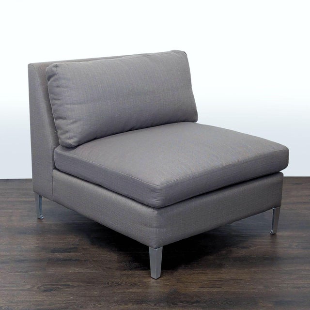 This CB2 lounge chair features a sleek and modern design with a soft gray fabric and sturdy metal legs. The wide,...