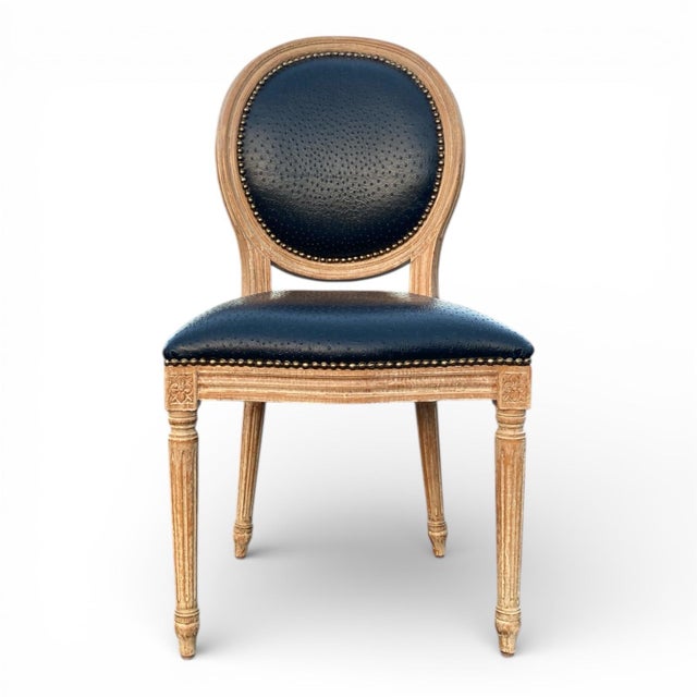 Stunning pair of elegant French Country Louis XVI-style side chairs, featuring distressed natural wood frames with carved...