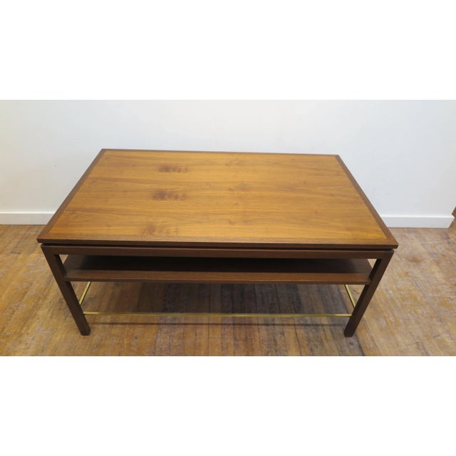 Dunbar cocktail table designed by Edward Wormley for Dunbar. Coffee table in two tone walnut with lower shelf and brass...