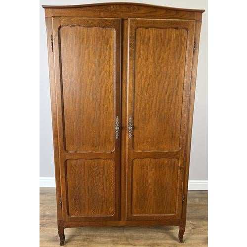 This elegant Vintage French Louis wardrobe showcases a beautifully grained oak finish, softly shaped panelled doors, and...