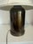 It features a heavy cylindrical metal base designed with a rich patina typical of mid-century neoclassical and Hollywood...