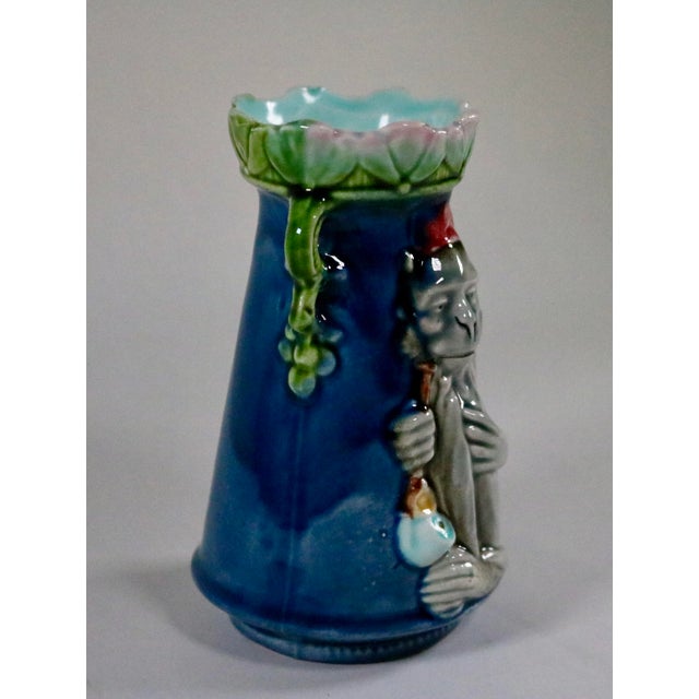 This item is a whimsical majolica monkey and pipe vase featuring brilliant colors, with a monkey wearing a fez hat and...