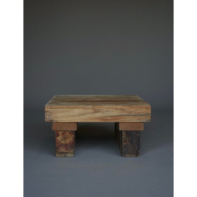 A small coffee table with a rough, unrestored Wabi Sabi or Brutalist appearance. It is made from thick sections of solid...