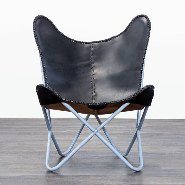 This butterfly lounge chair features a sleek black and brown leather seat with stitched detailing and a sturdy light blue...