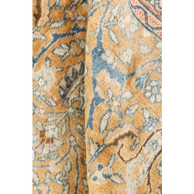 An early 20th century Persian Tabriz rug, the caramel field with an allover trellis of stylized palmettes, flowering...