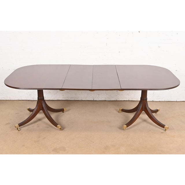 An exceptional Georgian or Regency style double pedestal extension dining table In the manner of Baker Furniture USA,...