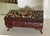 Early 1900's carved English box. Shell encrusted top. Lined in pink silk. On flared legs.