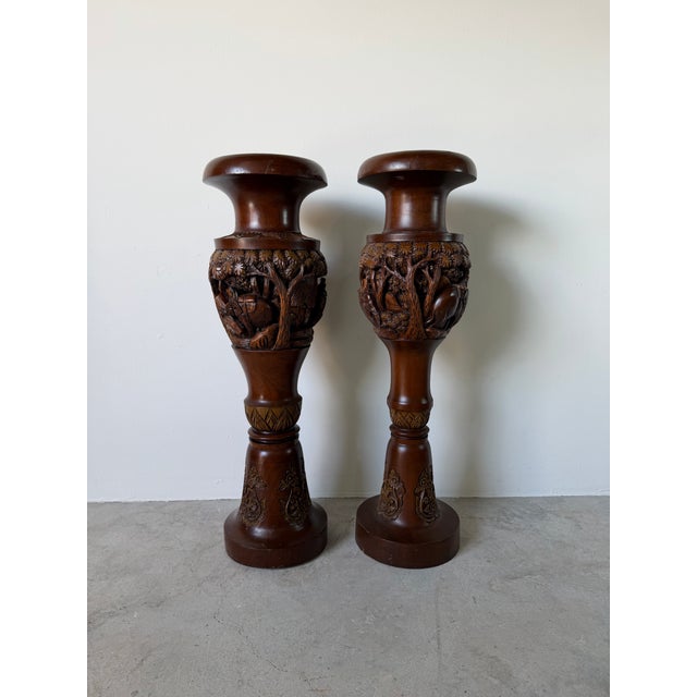 A striking pair of vintage handcrafted Asian floor vases, expertly carved from solid teak wood. These decorative vessels...