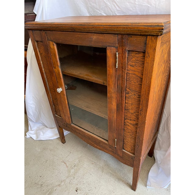 I believe this is an old radio or phonograph cabinet that has been repurposed to be used for storage or display items. The...