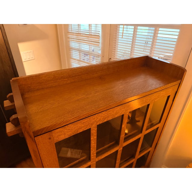 Stickley model 89-643 features a glazed door and geometric muntin’s, overhanging top featuring exposed through-tenon...