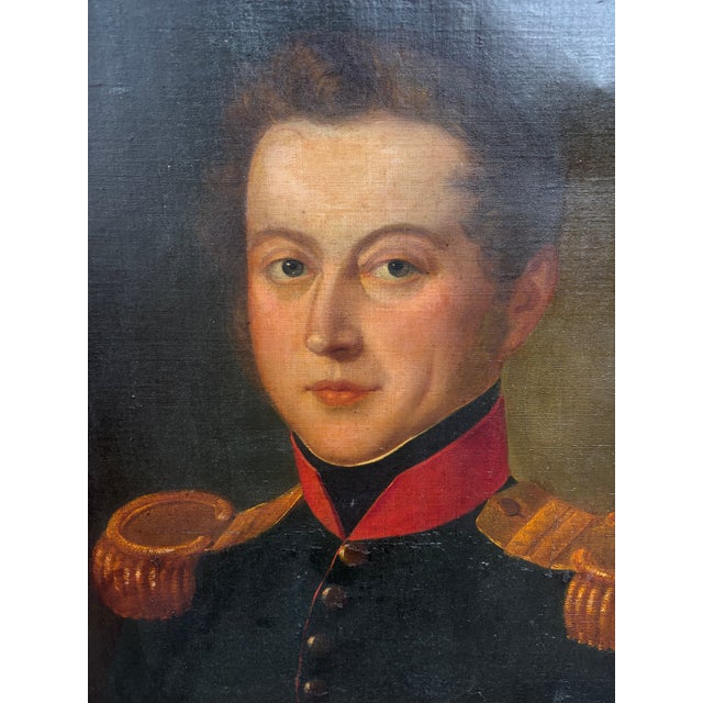 An early 19th century oil on canvas of an officer in a dark blue uniform with red collar and epaulets, probably British or...