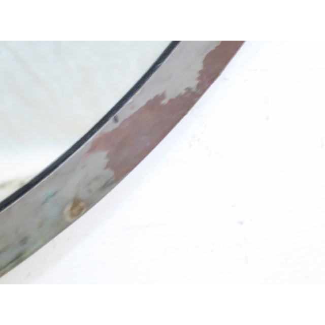 This round, solid bronze frame mirror has an old patinated finish.
