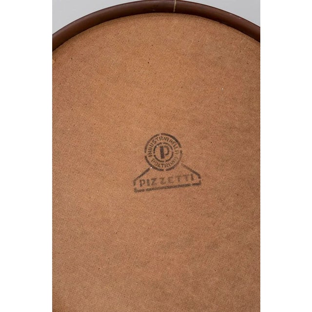 Round Italian mirror with a cognac-colored leather frame and hanging cord held by gilt-plated brass hinges. It retains the...